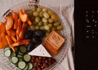 A delightful snack plate with fruits, cheese, and a laptop for a healthy lifestyle.
